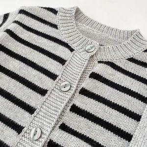 Detail of baby knit cardigan with grey and black stripes and polished shell buttons