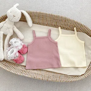Flat lay of ribbed knit baby camisoles and soft-sole shoes in a woven basket