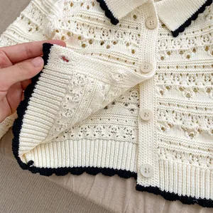 Cream knit cardigan for baby girls with hollow patterns and black scalloped edges