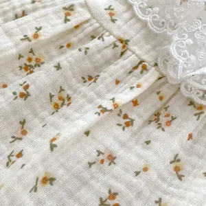 Detailed close-up of floral print cotton crepe fabric with delicate white lace collar trim