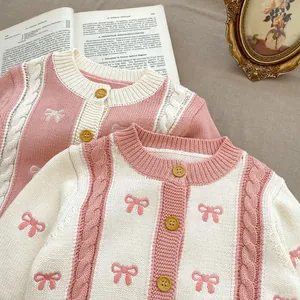 Close-up of pink knit cardigan with bow patterns and vintage cable stitch textures
