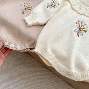 Detailed view of baby knit romper featuring delicate floral embroidery and lace collar