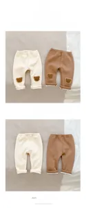 Detail of infant ribbed pants with bear embroidery in beige and caramel colors