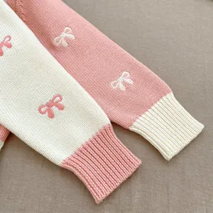 Detailed view of pink knitted sleeve with delicate bow embroidery and ribbed cuff texture