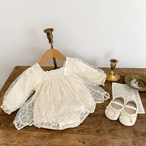 Dettaglio del pagliaccetto in pizzo crema per neonata con ricami e rete di tulle