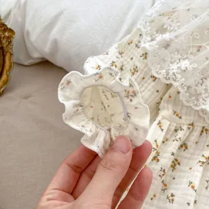 Detailed view of floral baby bodysuit with lace collar and elastic ruffled cuffs