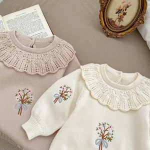 Detailed view of baby knit rompers with ruffle collars and floral embroidery patterns