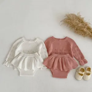 Detail van gebreide baby-set met opengewerkt patroon en ruches aan de randen