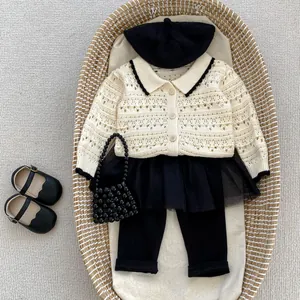 Flat lay of cream hollow knit cardigan with black mesh skirt and leggings set