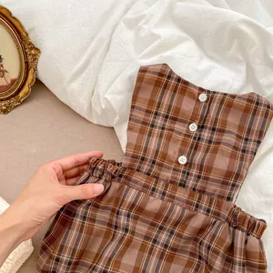Gros plan détaillé de la robe à carreaux vintage pour bébé avec boutons blancs