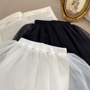 Detailed view of layered tulle skirts with elastic waistbands in black and cream beige