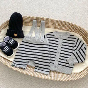 Flat lay of baby boy knit cardigan, striped romper, hat, and shoes in a cozy basket