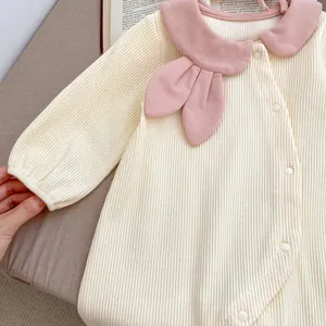 Detail of baby romper featuring pink Peter Pan collar and rabbit ear bow decoration