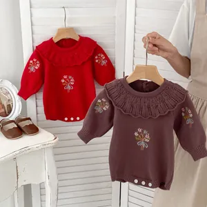 Detail of baby knitted romper showing ruffled collar and delicate floral embroidery