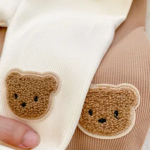 Detailed close-up of bear embroidery on elastic ribbed thermal baby pants fabric
