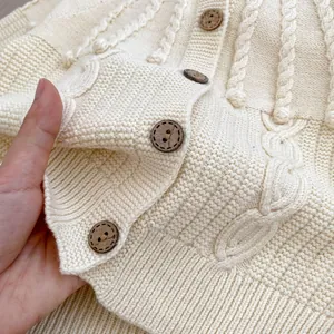 Cream knit baby cardigan with cable pattern and brown wooden buttons detail