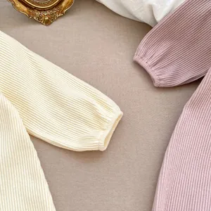 Detailed close-up of ribbed knit baby romper fabric with elegant scalloped collar