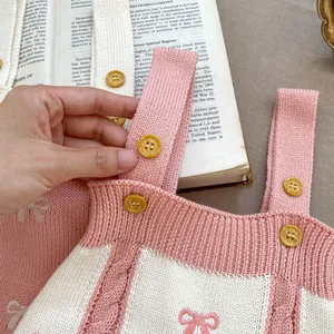 Close-up of pink and white checkered knit dress featuring rib straps and amber buttons