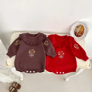 Close-up of knit baby romper featuring ruffled collars and floral embroidery details