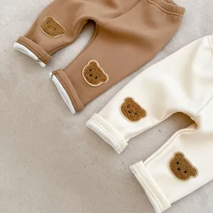 Detail of infant ribbed pants featuring cute plush bear patches and soft folded cuffs