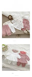 Détail de broderie cerise et col ondulé sur vêtement de détente en coton pour bébé