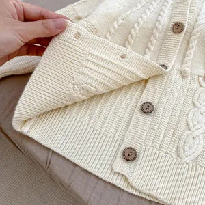 Detailed close-up of knitted beige cardigan with cable patterns and wooden buttons