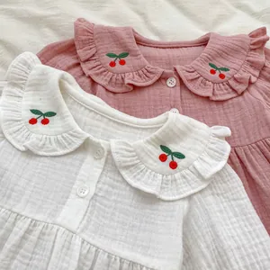 Détail de hauts pour bébé en gaze de coton avec broderie cerise et cols à volants