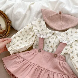 Close-up of floral baby shirt with lace collar and pink suspender dress set