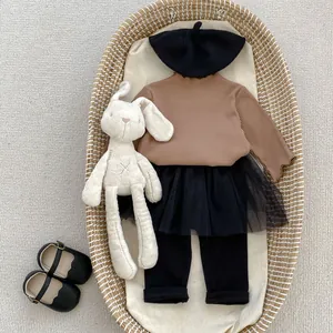 Flat lay of baby girl autumn outfit with brown knit top and black tulle skirt in a basket