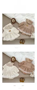 Detail von Baby-Baumwoll-Strampler-Kleid mit Bärenstickerei und weißer Spitzenkante