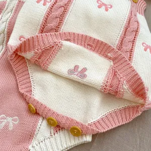 Detail of pink striped knit romper with cable stitch, bow embroidery and yellow buttons