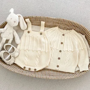 Detailed cable knit baby cardigan and romper set with wooden buttons in a basket