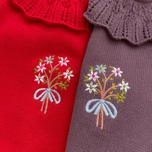 Detail of ruffled collar and floral embroidery on baby knit rompers in red and purple