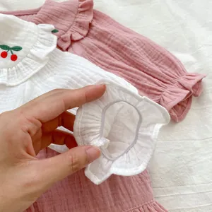 Détail des poignets élastiques à volants et broderie cerise sur coton doux pour bébé
