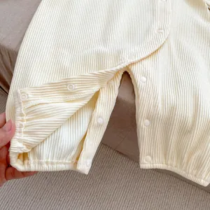 Detailed view of the ribbed fabric and snap buttons on this cream baby bodysuit