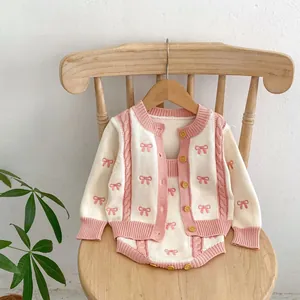 Detail of baby girl knitted cardigan and romper set with pink bows and yellow buttons