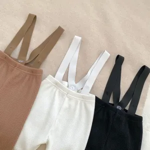 Detailed view of ribbed knit baby suspender pants in khaki, white and black colors