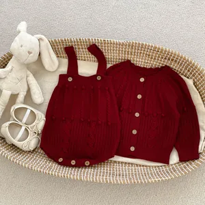 Flat lay of baby burgundy knitted romper and cardigan set with cute rabbit doll
