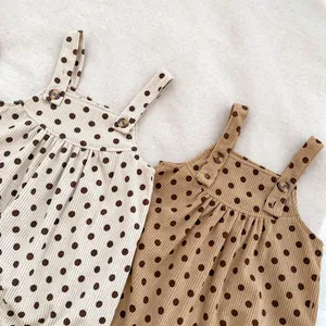 Detail of polka dot corduroy baby romper with shoulder straps and wooden buttons
