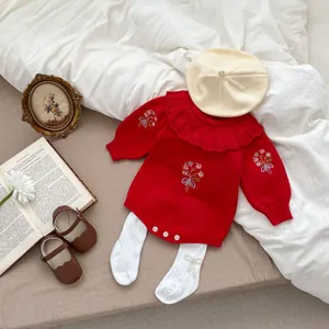 Detail of red knit baby romper with floral embroidery and lace ruffle collar