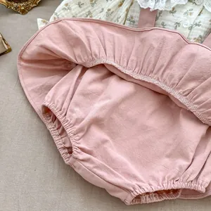 Close-up of baby girl pink cotton overalls with lace floral shirt detail