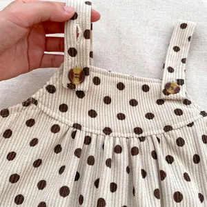 Detailed close-up of corduroy baby romper showing polka dots and adjustable marble button straps