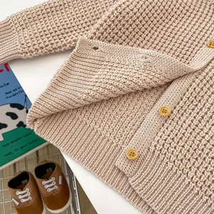 Detalle de cárdigan de punto gofrado beige con botones de madera y puños acanalados