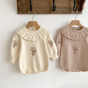 Detail of baby knitted bodysuit featuring ruffled collar and delicate floral embroidery