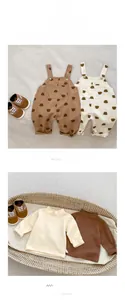 Detail von Baby-Langarmshirts und Bären-Latzhosen in Creme- und Brauntönen