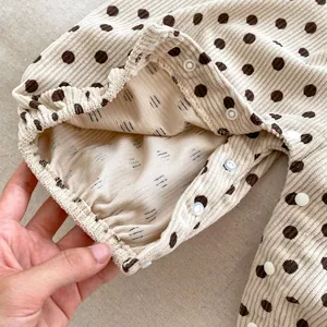 Close-up of baby romper showing polka dot corduroy fabric with ruffles and snap buttons