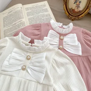 Details von Baby-Bodys mit großen weißen Schleifen und eleganten Perlenknöpfen