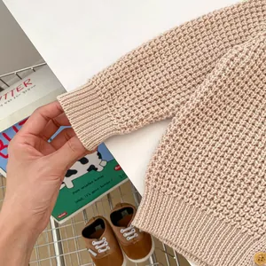 Detalle de cárdigan beige de punto gofrado con puños acanalados y botón de madera