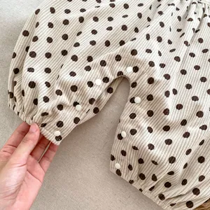 Close-up of baby corduroy romper featuring polka dot patterns and snap button closure