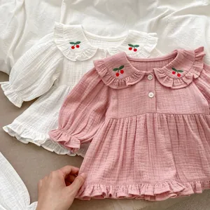 Détail de vêtements en coton pour bébé avec broderie cerise et col à volants doux